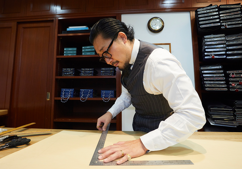 カッター（裁断師）が接客とフィッティングをし、テーラーがカッターの指示を仰いで縫い上げ、その人だけの完璧な一着を作り上げる