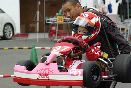プロレーシングドライバーになると決意した5歳のJujuさん。後ろはお父様の英樹さん。この年、カートレースの30cc/40ccクラスでダブルチャンピオンを獲得。
