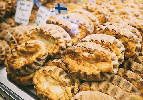 ライ麦の薄い生地で米粥を包んだ「カレリアパイ」は、東部カレリア地方に由来する伝統食。地域によっては大麦やジャガイモを詰めることもあり、携帯しやすい主食として親しまれてきた。